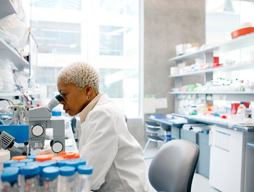 Person examining samples under a microscope in a laboratory
