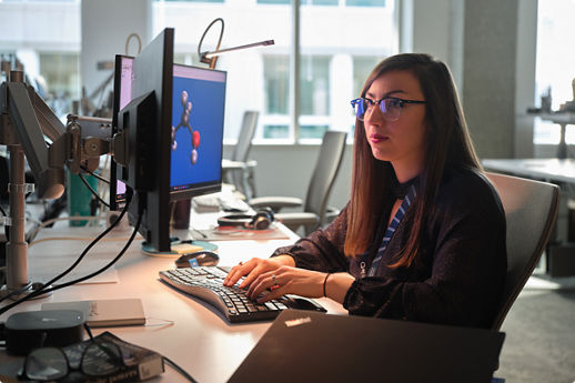 Person working at dual monitors with a molecular model on screen
